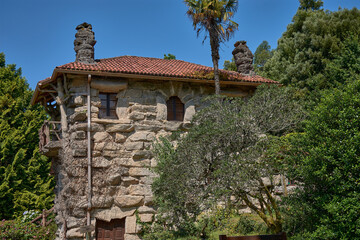 Rustic stone facade of the Monte Aloia Park Interpretation Center under a clear sky and bright light