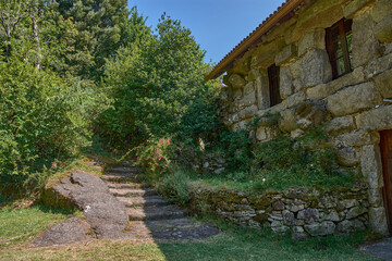 Rustic stone facade of the Monte Aloia Park Interpretation Center under a clear sky and bright light