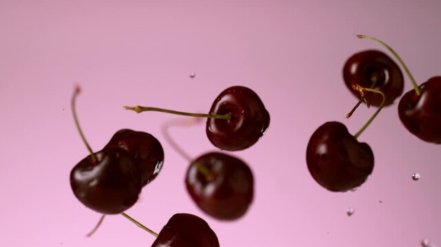 Cherries flying in slow motion on pink background
