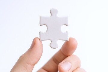 Obraz premium Hand Holding Single Puzzle Piece Isolated on White Background, Symbolizing Solution, Teamwork, and Strategy