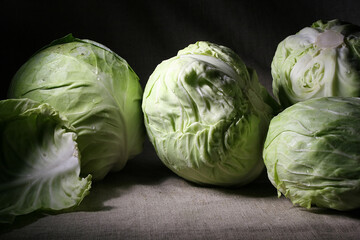 Still life with green young cabbage on dark background