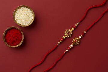 Traditional rakhi with rice and kumkum, red background, Raksha Bandhan festival, Indian celebration, brother sister bond