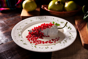 Chiles en Nogada, Typical dish from Mexico. Prepared with poblano chili stuffed with meat and fruits and covered with a walnut sauce, parsley and pomegranate.