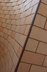 A straight seam line separates the flat and curved surfaces of a brick wall
