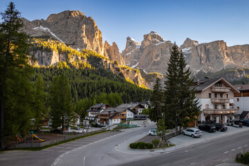 Colfosco village in the Dolomites with golden sunset colours on the rocky slopes of Piz Boè mountain