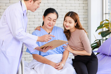 Fototapeta premium Asian man professional doctor visiting ward talking giving report good news to smiling and happy family and senior woman patient sitting on hospital bed with lovely daughter showing healthcare support