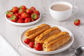 Delicious eclairs served with fresh strawberries and coffee in a cozy breakfast setting