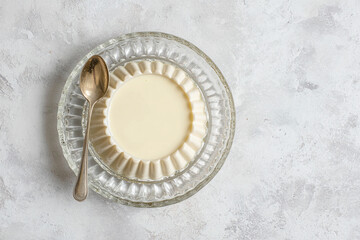 Fototapeta premium A panna cotta dessert in a glass dish with a spoon on a textured surface
