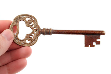 A person's hand holding an old, ornate, antique bronze skeleton key against a plain white background.
