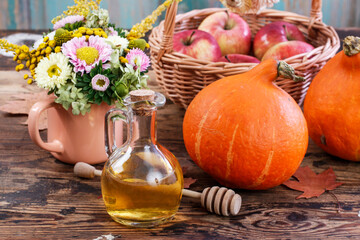 Glass bottle of honey and ripe pumpkins on the table.