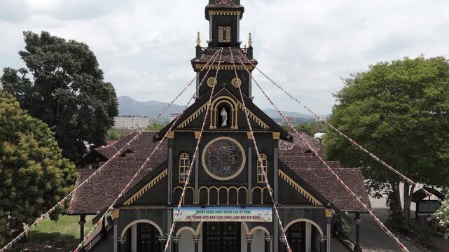 Ascending drone footage in front of an unique wooden church, the black cathedral of Kon Tum city, 100 years old, Vietnam