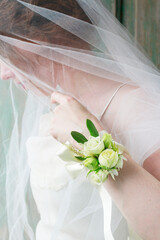 Bride wearing wrist corsage made of rose and eustoma flowers.