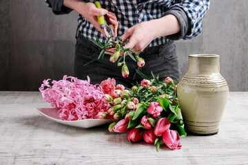 Florist at work: woman shows how to make spring bouquet with tulip, hyacinth and carnation flowers. Step by step, tutorial.
