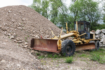 An old-style bulldozer at a pile of small stones.