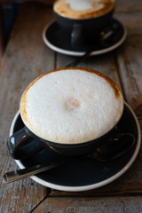 two cups of cappuccino and caffe latte coffee on old wooden table