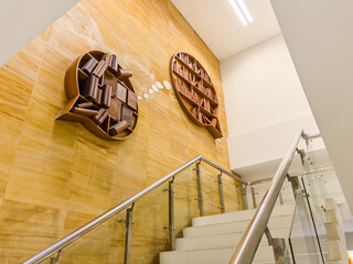 Modern library interior with creative circular wooden bookshelves mounted on marble wall,...