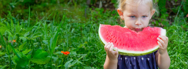 Happy child eating watermelon on the street. Summer time