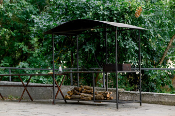 Barbecue area. Metal structure with barbecue and woodpile