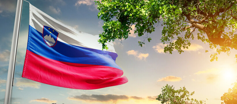 Slovenia national flag waving in the sky behind the tree. The flag blow in beautiful sunlight. Slovenia national flag for independence day.