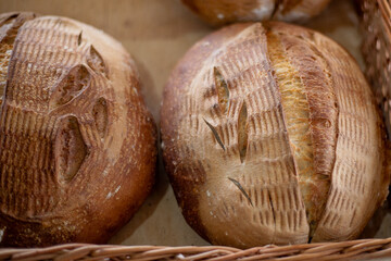 Craft sour homemade bread in a straw basket in a bakery. Sale of bread and bakery products....