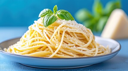 Pasta with Parmesan cheese and basil on a blue table.