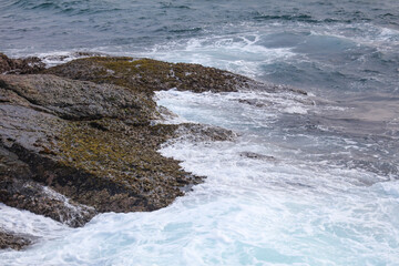 Fototapeta premium The ocean is rough and the rocks are covered in moss
