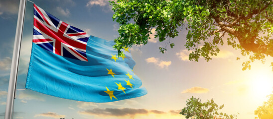 Tuvalu national flag waving in the sky behind the tree. The flag blow in beautiful sunlight. Tuvalu...