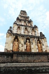 Fototapeta premium Ancient Brick Chedi with Standing Buddha Statues at Wat Chamthewi in Lamphun, Thailand – Hariphunchai Architecture