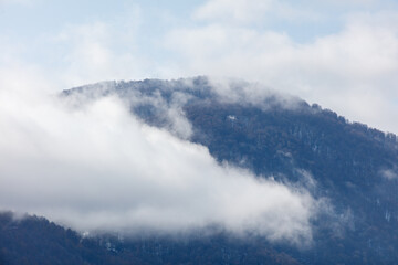 The sky is cloudy and the mountain is covered in trees