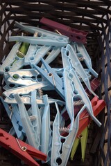 A group of blue plastic clothespins collected in a basket, close-up shot with selective focus....