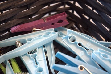 A group of blue plastic clothespins collected in a basket, close-up shot with selective focus....