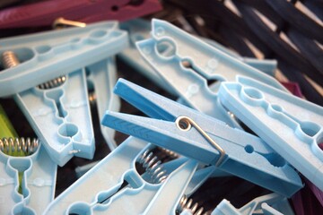 A group of blue plastic clothespins collected in a basket, close-up shot with selective focus....