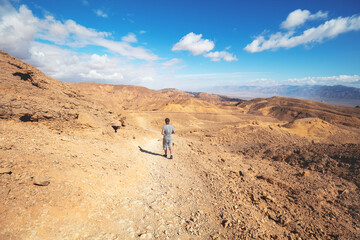 The young man is hiking in the desert on a sunny day. Eilat mountains in the Negev desert, Israel
