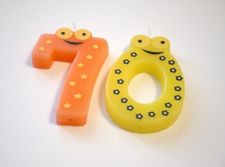 Close-up of a birthday candle in the shape of number 70 on a clean white background. Isolated with...