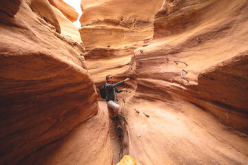 The young man is climbing a canyon in a dry riverbed in the desert. Red Canyon in the Negev desert, Israel
