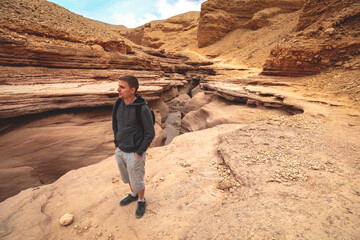 Dry river bed, wilderness. Desert natural landscape. Sandstone texture. Young man walking in Red Canyon in the Negev Desert near Eilat, Israel.