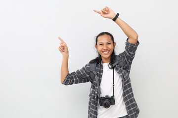 A young asian traveler wearing casual clothes, backpack, camera on neck, pointing to the side in...