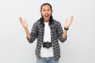 A young asian man amazed looking at something, wearing casual clothes, backpack, camera hanging on...