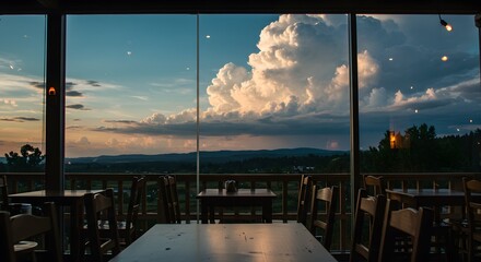 Scenic view from a restaurant window of a dramatic cumulus cloud at sunset over a rolling landscape.