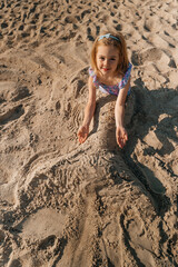 Child playing in sand creating a sand sculpture on a sunny beach during the afternoon