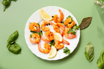 Cooking fried shrimps with aromatic spices and lemon in a plate isolated on green