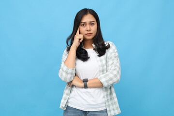 Serious young Asian woman looking at camera, wearing casual clothes, holding finger on her temple,...