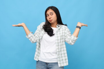 Young asian woman confused and clueless, hesitant, shrugging her shoulders open her arms, showing...