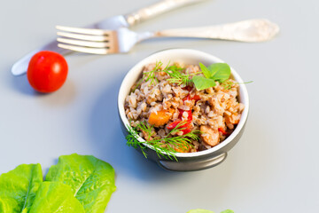 Bowl with buckwheat and vegetables on a gray background