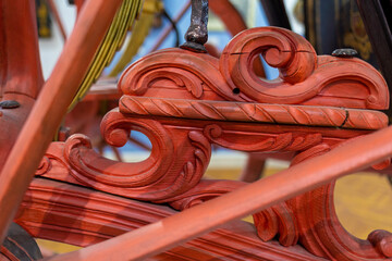 Close-up of carved wooden parts of a carriage painted in red. History and transportation.