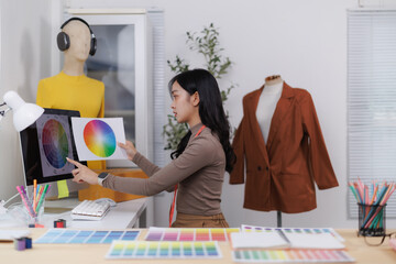 Fashion designer comparing color palettes on computer and paper in her studio