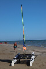 Sailor preparing catamaran on sandy beach for sailing in sunny day