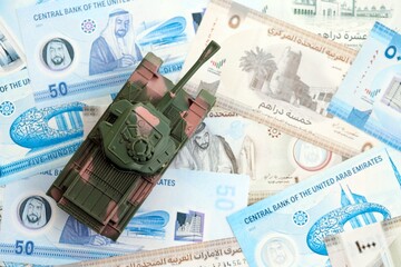 United Arab Emirates dirham currency money bills and toy tank. The concept of army funds and...