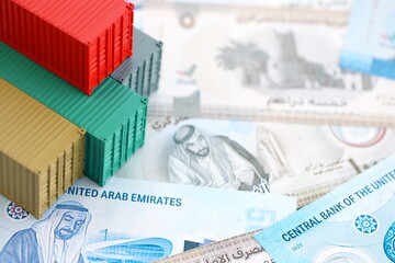 United Arab Emirates dirham currency money bills and toy cargo containers. The concept of shipping and logistics