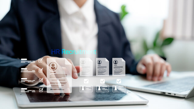 Hr manager using digital tablet and laptop for HR recruitment, screening resumes with virtual interface, selecting qualified candidates through smart hiring technology.